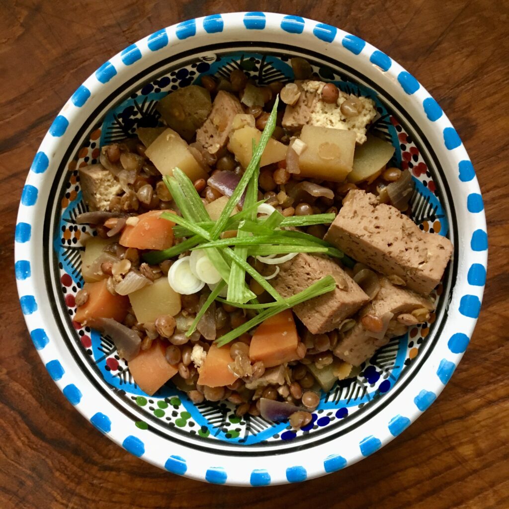 Bunte Marokkanische Schüssel mit Linseneintopf und viel Tofu, darauf ein paar Streifen Frühlingszwiebel